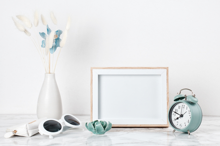 Poster frame mockup, front view, with decor elements and female accessories, flowers and blank copy space over the white wall.の写真素材