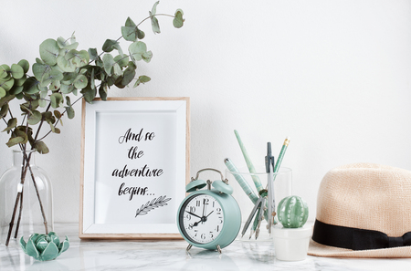 Poster framewith tiped text: Adventure begins, front view, with decor elements and female accessories, flowers and blank copy space over the white wall.の写真素材