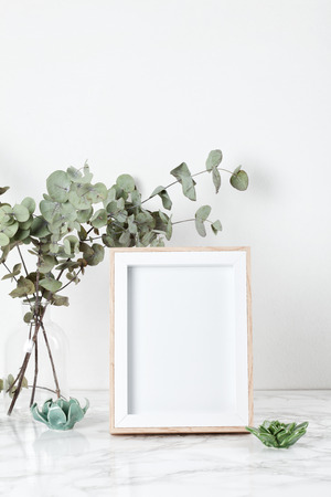 Poster frame mockup, front view, with decor elements, flowers and blank copy space over the white wall.の写真素材