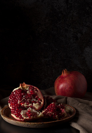 Still life with red juicy pomegranates over dark background. Organic Bio fruitsの写真素材