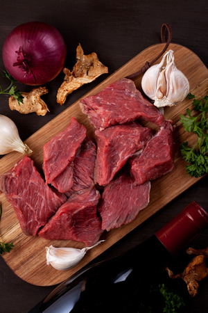 Raw fresh meat, bottle of wine and seasonal autumn organic vegetables on wooden board ready for cookingの写真素材