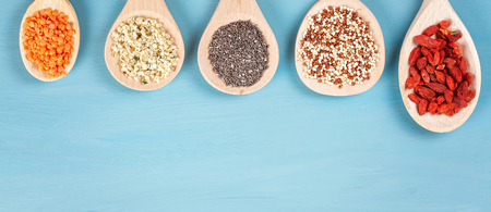 Various superfoods goji berries, quinoa, chia, hemp seeds and lantils on blue background. Vegan, vegetarian and healthy eating diet and organic products conceptの写真素材