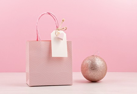 Creative image of pink gift bag with empty tag, heart and christmas decoration. Christmas shopping, sales and presents conceptの写真素材