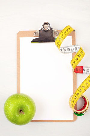 Clipboard with apple and measuring tape for diet, weight loss and fitness planning. Healthy lifestyle conceptの写真素材