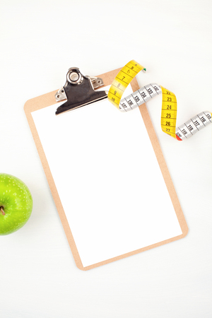 Clipboard with apple and measuring tape for diet, weight loss and fitness planning. Healthy lifestyle conceptの写真素材