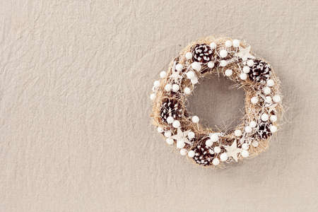 Top view of traditional Christmas wreath with copy space over neutral linen tissue background. Winter holidays and Christmas celebration conceptの写真素材