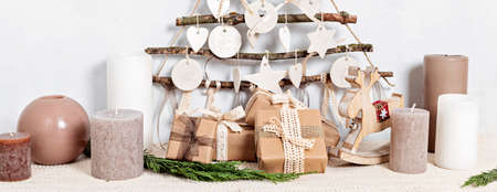 Zero waste christmas with gifts wrapped in craft paper and alternative handmade xmas tree hanging over light wallの写真素材