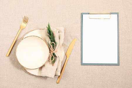 Christmas festive menu mockup scene. Empty plate and fir tree branches on linen table cloth in natural neutral colors. Holiday background. Flat lay, top viewの写真素材