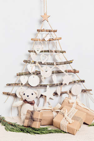 Zero waste christmas with gifts wrapped in craft paper and alternative handmade xmas tree hanging over light wallの写真素材
