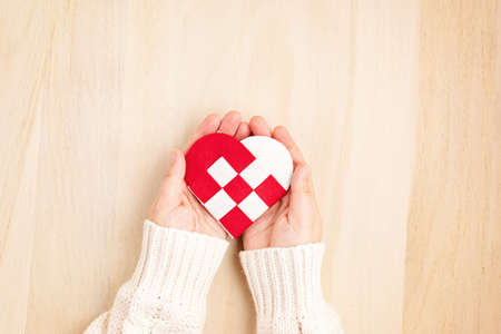 Giving Tuesday concept with woman hands holding red and white heart, charity day concept. Donation, philantropy, help and support idea.  Top view, flat layの写真素材