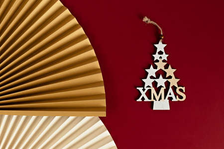 Closeup of a decorative Christmas tree made of golden stars with a paper fan on red background....
