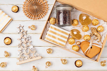 Preparing care package, seasonal gift box with coffee, cookies and chocolates. Personalized eco friendly basket for family and friends for christmas in golden colors.の写真素材