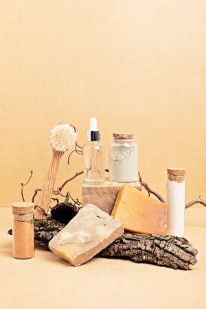 Natural serum, dry soap and clay masks displayed with pieces of wood on sand beige background. Presentation of organic eco friendly spa beauty products in neutral colors nature environmentの写真素材