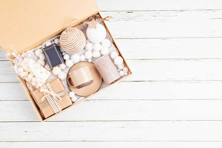 Preparing care package, seasonal gift box with tea, candle, cup and xmas ornaments. Personalized eco friendly basket for family and friends for christmas. Top view, flat layの写真素材