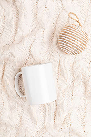 Mockup with white mug and eco friendly Christmas ornaments on knitted background. Assortment of cozy hygge Xmas decorations with copy space for text on blank cup. Flat lay, top viewの写真素材