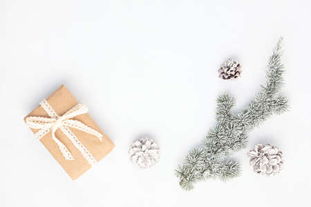 Christmas tree branch and gift box wrapped in organic craft paper on white background, flat lay, top view, copy space. Winter holidays, xmas greeting cardの写真素材