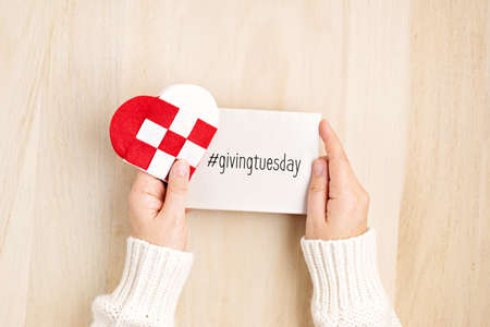 Giving Tuesday concept with woman hands holding red and white heart, charity day concept. Donation, philantropy, help and support idea.  Top view, flat layの写真素材