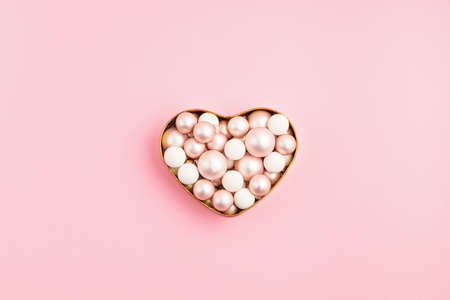 Christmas ornanemts in heart shaped box on pink backdrop. Xmas greeting card minimal background. Top view, copy space, flat layの写真素材