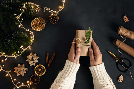 Woman hands wrapping Eco friendly alternative green Xmas gifts with recycled craft paper. Zero waste...