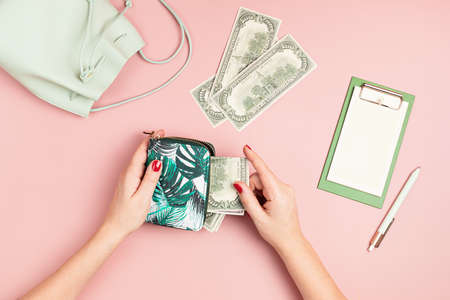 Woman hands taking money out of purse on pink background. Concept of pay, shopping, wealth,...
