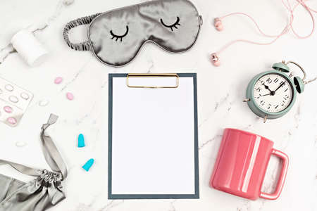Classic alarm clock, sleeping mask, clipboard and tea cup. Minimal concept of rest, quality of...