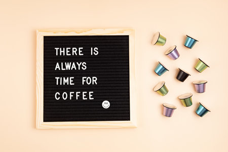 There is always time for coffee text on letter board. Top view of coffee capsules over beige backgroundの写真素材
