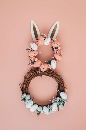 Easter bunny made of wreath of eggs and flowers over pink pastel backgroundの写真素材