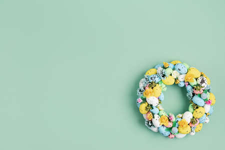Handmade diy home interior decoration wreath with colorful easter eggs over green background