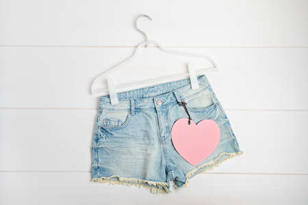 White rack with heart tag and jeans shorts. Slow fashion concept mockupの写真素材