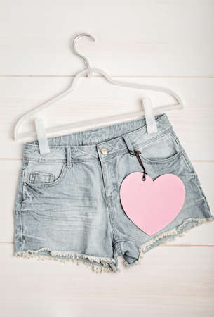 White rack with heart tag and jeans shorts. Slow fashion concept mockupの写真素材