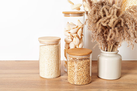 Assortment of grains, cereals and pasta in glass jars on wooden table. Zero waste kitchen storage