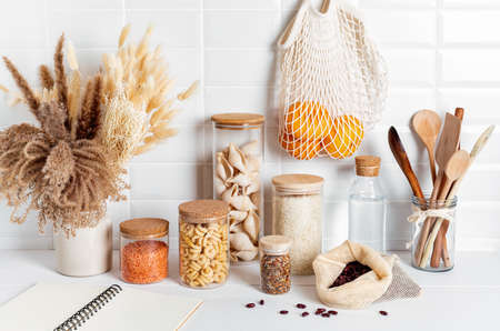 Assortment of grains, cereals and pasta in glass jars and kitchen utensils on wooden tableの写真素材