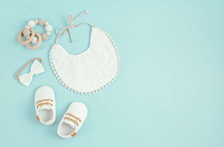 Baby shoes, bib and teether on blue background. Organic newborn accessoriesの写真素材