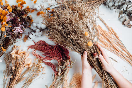 Woman composing bouquet of dry flowers and herbs