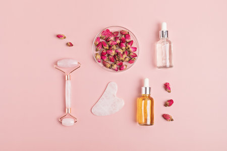 Rose quartz face roller, gua sha stone, essential oil and dry rosesの写真素材