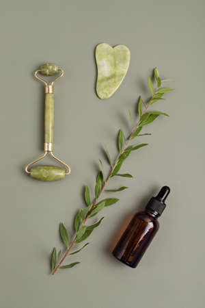 Green jade face roller, gua sha stone, essential oil. Natural skin careの写真素材