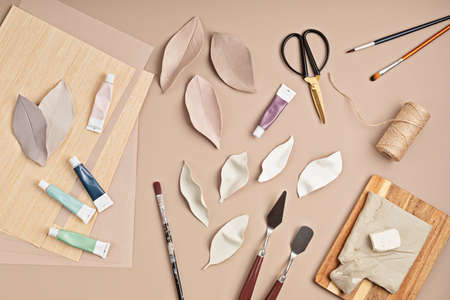Hobby background with handmade clay leaves, paint brushes and art accessories