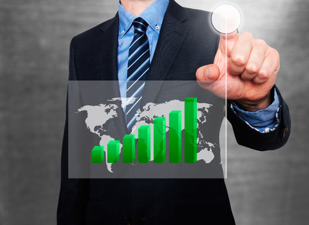 Businessman in dark suit pushing button worldmap global Growth. Green Graph going up. Grey backgroundの写真素材