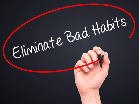 Man Hand writing Eliminate Bad Habits with black marker on visual screen. Isolated on black. Business, technology, internet concept. Stock Photoの写真素材