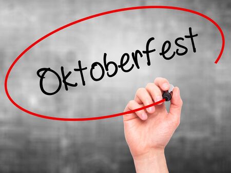 Man Hand writing Oktoberfest with black marker on visual screen. Isolated on grey. Business, technology, internet concept. Stock Photoの写真素材