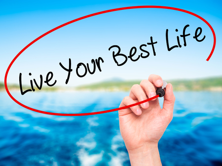 Man Hand writing Live Your Best Life with black marker on visual screen. Isolated on nature. Business, technology, internet concept. Stock Photo Man Hand writing Live Your Best Life with black marker on visual screen. Isolated on nature. Business, technology, internet concept. Stock Photo