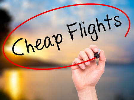 Man Hand writing Cheap Flights with black marker on visual screen. Isolated on nature. Business, technology, internet concept. Stock Imageの写真素材