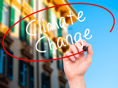 Man Hand writing Climate Change with black marker on visual screen. Isolated on city. Business, technology, internet concept. Stock Photoの写真素材