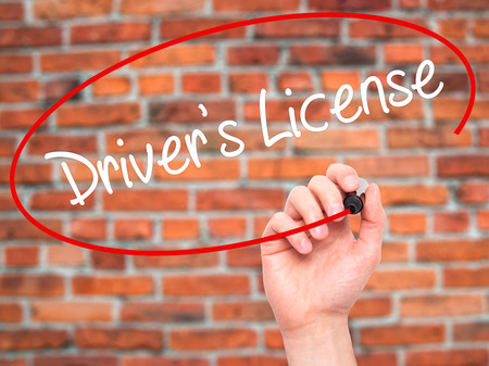 Man Hand writing Drivers License with black marker on visual screen. Isolated on bricks. Business, technology, internet concept. Stock Photoの写真素材