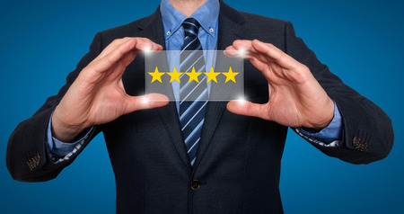 Businessman holding five star rating. Blue - Stock Image