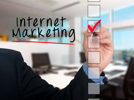 Businessman hand writing Internet Marketing and check listing task. Isolated on office background. Stock photoの写真素材