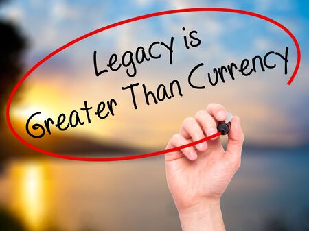 Man Hand writing Legacy is Greater Than Currency with black marker on visual screen. Isolated on background. Business, technology, internet concept. Stock Photo