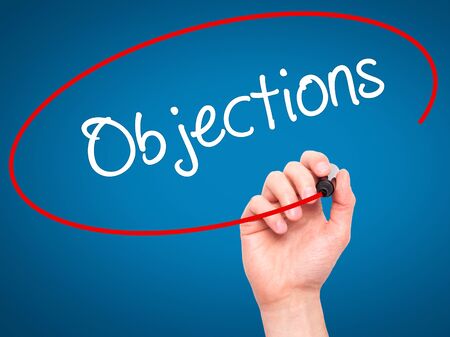 Man Hand writing Objections  with black marker on visual screen. Isolated on blue. Business, technology, internet concept. Stock Photoの写真素材