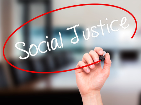 Man Hand writing Social Justice with black marker on visual screen. Isolated on office. Business, technology, internet concept. Stock Photoの写真素材