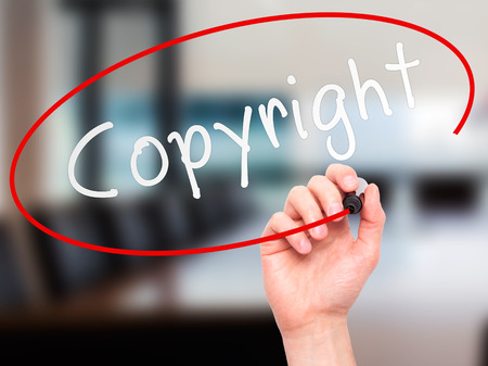 Man hand writing Copyright on visual screen. Business,help, internet, technology concept. Isolated on office. Stock Photoの写真素材